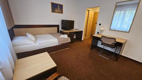 a bedroom with a bed and a desk and a television at Hotel Adler in České Budějovice