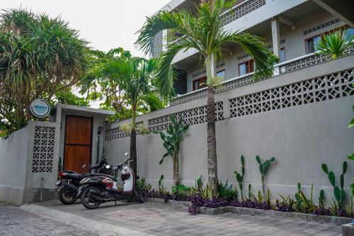 a motorcycle parked in front of a house with palm trees at The Breeze Stay and Surf Canggu Bali in Canggu