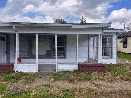 ein weißes Haus mit einem roten Stuhl davor in der Unterkunft Cozy 2 Bed Retreat in Vibrant Beaumont, TX in Beaumont