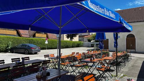a group of tables and chairs under a blue umbrella at Gasthof Zur Post - Inning in Inning am Ammersee