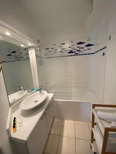 une salle de bain blanche avec un lavabo et une baignoire dans l'établissement Appartement Les Hameaux du Port, à Cabourg