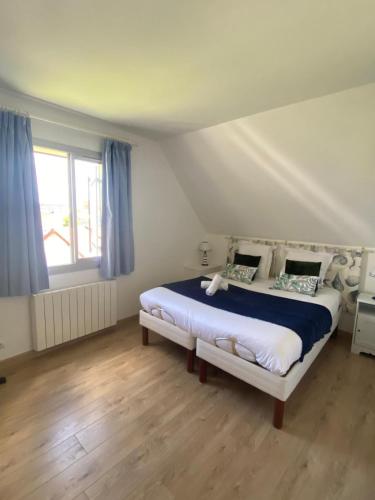 une chambre avec un lit et une fenêtre avec des rideaux bleus dans l'établissement Appartement Les Hameaux du Port, à Cabourg