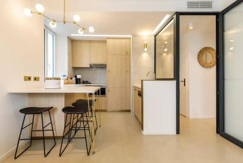 La cuisine est équipée d'un comptoir, d'un réfrigérateur et de tabourets. dans l'établissement Palais Croisette Plage - 45 m2 Luxe - 2 Balcons, à Cannes