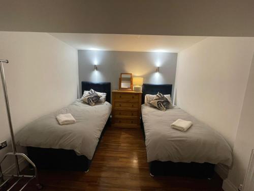 a bedroom with two beds and a dresser at No1 Apartment Mevagissey in Mevagissey