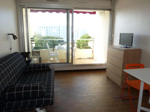 un salon avec un canapé, une télévision et une fenêtre dans l'établissement Studio cabine, piscine, proche plage et commerces - FR-1-328-219, à La Grande Motte