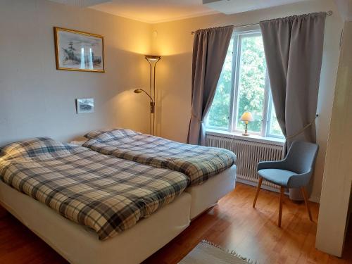 a bedroom with two beds and a chair and a window at Flora Dekor gästgård, Lenagården in Alingsås