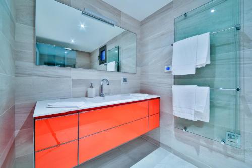 La salle de bains est pourvue d'un lavabo orange et d'une douche en verre. dans l'établissement 7 Croisette, à Cannes