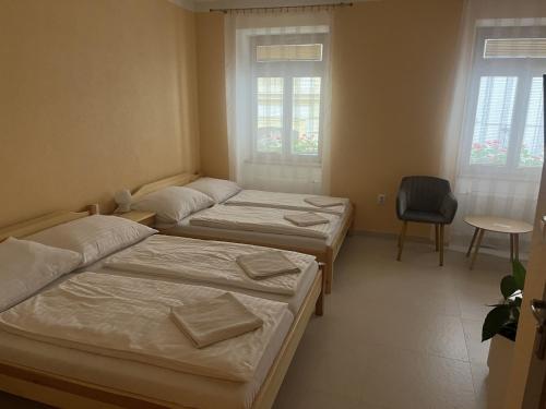 two beds in a room with a chair and two windows at VT6 House & Restaurant in Znojmo