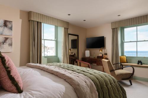 a bedroom with a large bed with a chair and windows at Pier House in St Austell