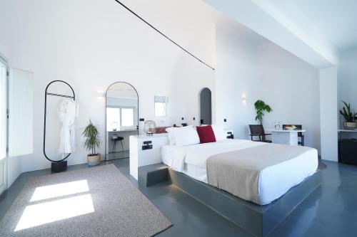a white bedroom with a large bed and a mirror at Santonero in Akrotiri