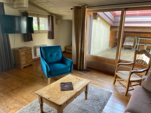 un salon avec une chaise bleue et une table dans l'établissement Appartement 71m2 près de Megève, 2 chambres, terrasse en toiture, parking couvert, tennis en été, à Demi-Quartier