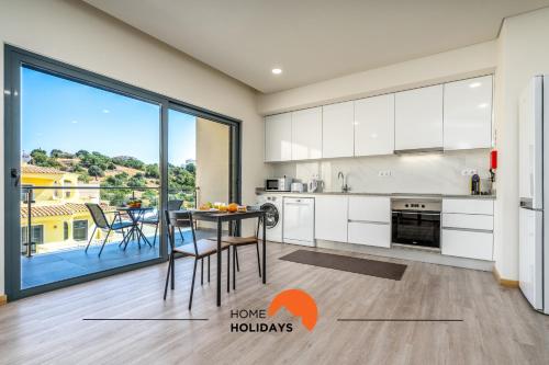 a kitchen with white cabinets and a table at #234 Serenity Refuge w Balcony and Pool in Páteo