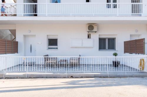 a white building with a white fence in front of it at Sandra Seaview Suites in Neos Marmaras