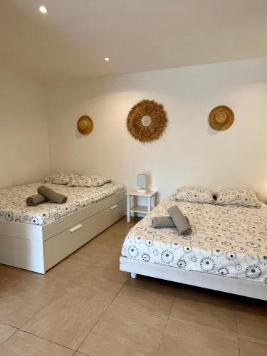 une chambre avec deux lits et un miroir au mur dans l'établissement Villa Bahia - bas de villa en pleine nature !, à Saint-Mitre-les-Remparts