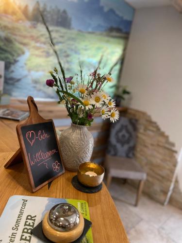 a table with a vase of flowers and a book at Heisshof in Schladming
