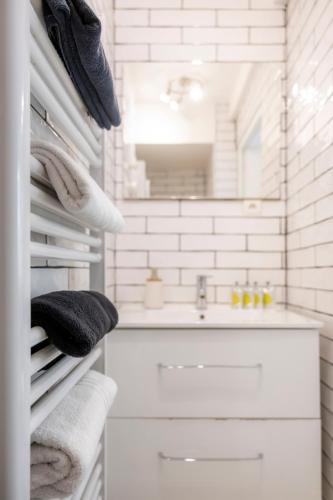 La salle de bains blanche est pourvue d'un lavabo et de serviettes. dans l'établissement T3 à proximité de la gare et du telecabine, à Briançon