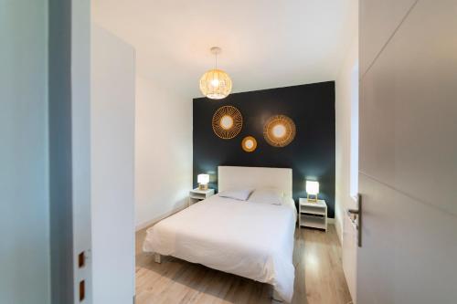 - une chambre avec un lit blanc et deux lampes dans l'établissement T3 à proximité de la gare et du telecabine, à Briançon