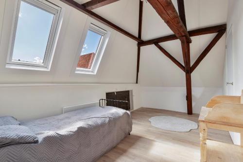 a bedroom with a bed and two windows at De Kleine Lantaarn in Bergen op Zoom