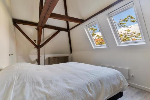 a bedroom with two windows and a white bed at De Kleine Lantaarn in Bergen op Zoom