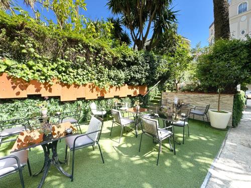 a patio with tables and chairs on the grass at Hôtel de Provence in Cannes