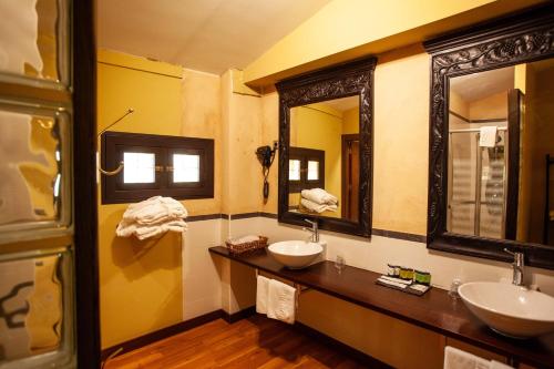 a bathroom with two sinks and two mirrors at Hotel El Doncel in Sigüenza