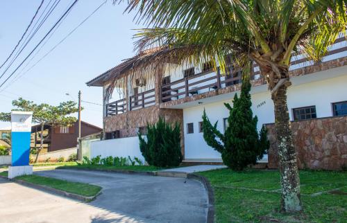 a building with a palm tree in front of it at Toya Hotel in Ilha Comprida