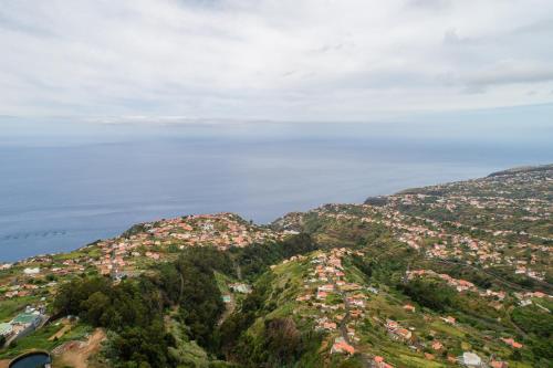 a view of a mountain with houses and the ocean at Florenças House - Private Jacuzzi & Garden in Calheta