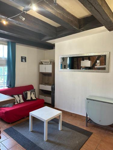 un salon avec un canapé rouge et une table dans l'établissement Gîtes Place Plumereau de Tours, à Tours