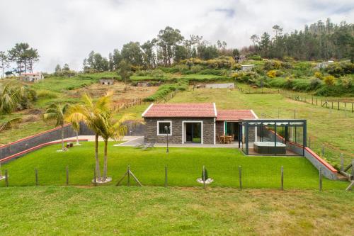 a house on a hill with a green yard at Florenças House - Private Jacuzzi & Garden in Calheta