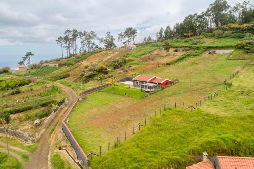 a house on a grassy hill with a fence at Florenças House - Private Jacuzzi & Garden in Calheta
