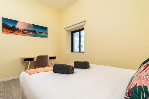 a bedroom with a bed and a desk and a window at Florenças House - Private Jacuzzi & Garden in Calheta