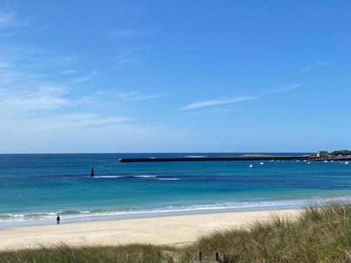 a beach with people in the water and a pier at Penty de charme - Plogoff Pors Loubous in Plogoff