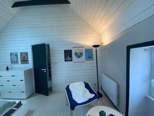 a bedroom with a blue chair and a lamp in a room at Penty de charme - Plogoff Pors Loubous in Plogoff