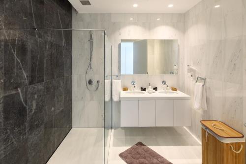a white bathroom with a shower and a sink at Minthis Resort in Paphos City