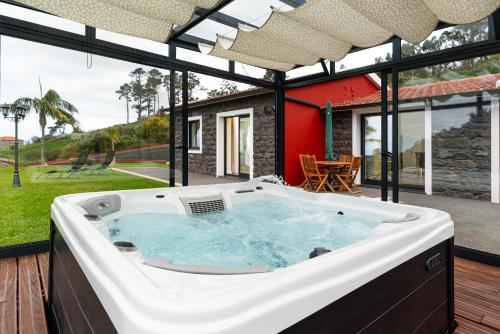 a hot tub on a deck with a house at Florenças House - Private Jacuzzi & Garden in Calheta