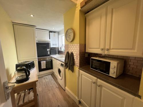 a kitchen with white cabinets and a clock on the wall at 34-2 mansfield road in Hawick