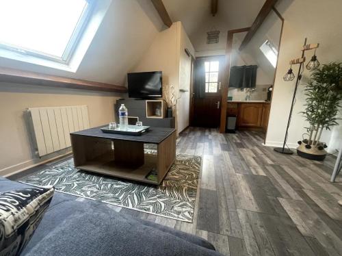 un grand salon avec une télévision et une table dans l'établissement Studio, Escale GREEN, à Saint-Valery-en-Caux