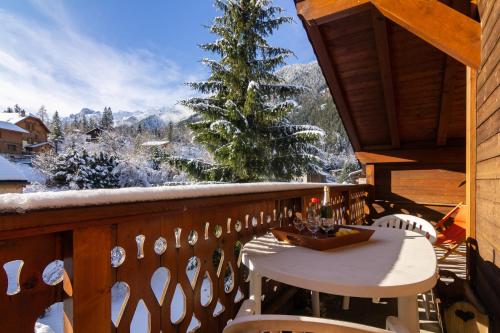 Una mesa y sillas en un balcón con un árbol de Navidad. en Appartement Les Drus 118 - Happy Rentals, en Chamonix-Mont-Blanc