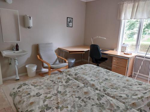 a bedroom with a bed and a desk and a sink at Flora Dekor gästgård, Lenagården in Alingsås