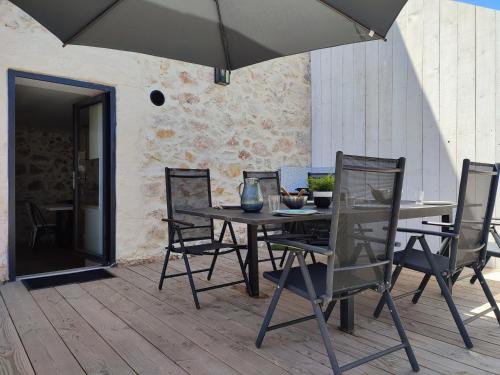 une table et des chaises avec un parasol sur une terrasse dans l'établissement Le Petit Bivouac, à Saint-Bauzille-de-Putois