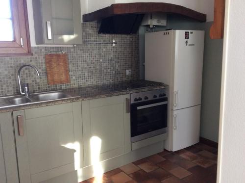 a kitchen with a white refrigerator and a sink at La maison de Chantal in Barizey