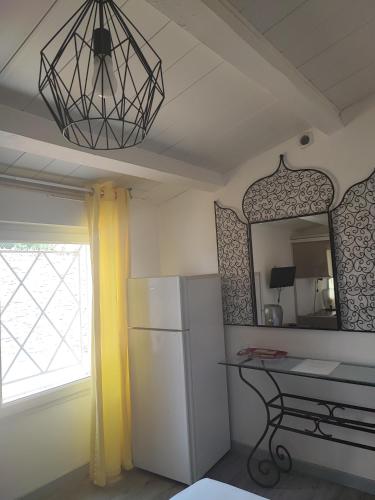 La cuisine est équipée d'un réfrigérateur blanc et d'un miroir. dans l'établissement Chambre avec piscine, au Cap d'Agde