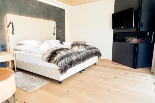 a bedroom with a bed with a faux fur blanket at Hotel Gran Paradiso in San Cassiano
