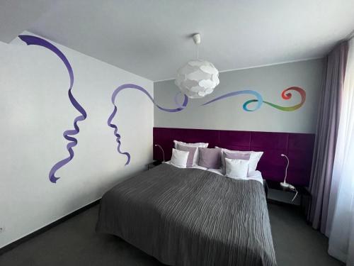 a bedroom with a bed with a painting of two faces at Canpol-Jull's Art Hotel in Człuchów