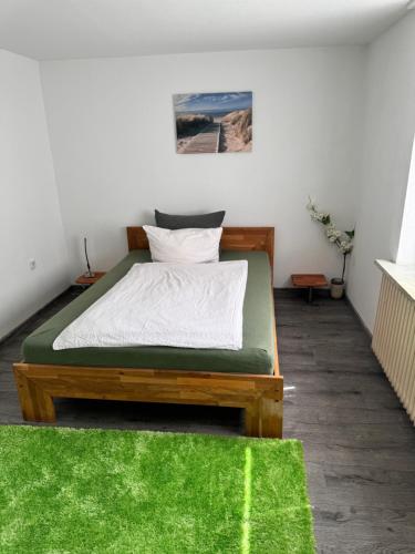 a bedroom with a bed with a green rug at Nordsee Wohlfühloase in Norden