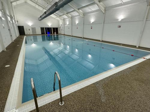 a large swimming pool with blue water in a building at The Puffin Pad in Filey
