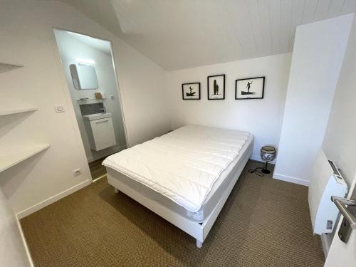 - une petite chambre avec un lit blanc et un miroir dans l'établissement Jolie villa dans les pins avec piscine chauffée et wifi, à La Tranche-sur-Mer