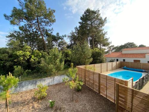 - une piscine dans un jardin avec une clôture en bois dans l'établissement Jolie villa dans les pins avec piscine chauffée et wifi, à La Tranche-sur-Mer
