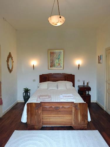 une chambre avec un grand lit en bois dans une pièce dans l'établissement La Maison des Artistes, à Laguépie