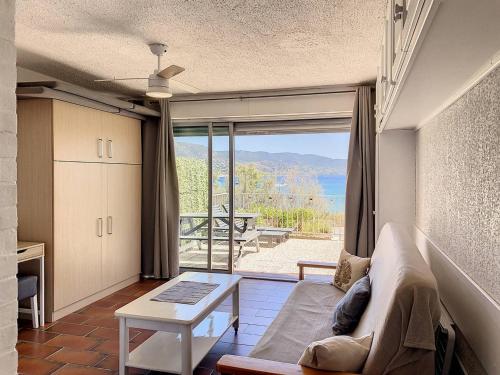 un salon avec un canapé et une vue sur l'océan dans l'établissement Studio en bord de mer, rez de jardin, accès plage - FR-1-610-90, à Bormes-les-Mimosas